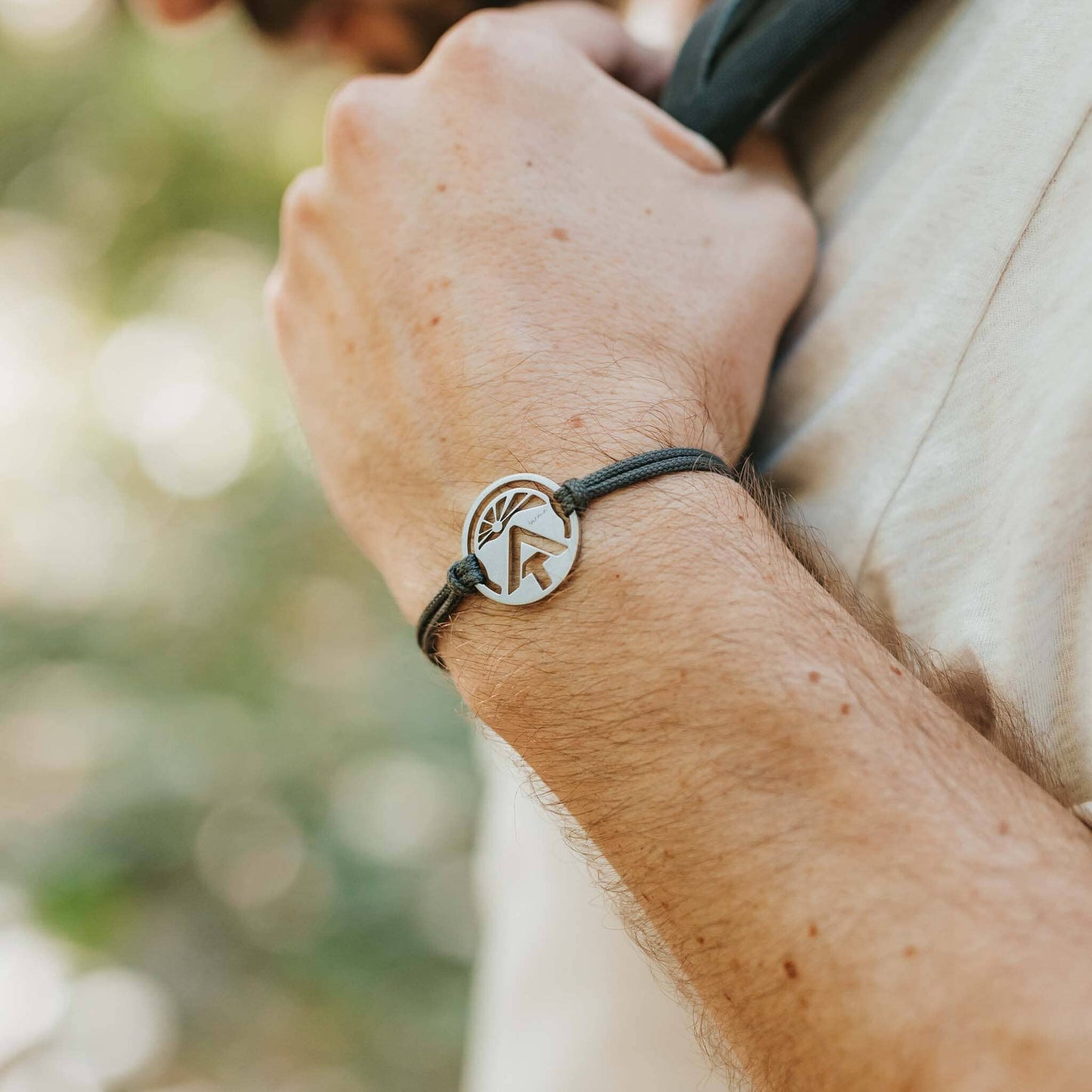 Man wearing stainless steel appalachian trail sunburst pendant on black paracord