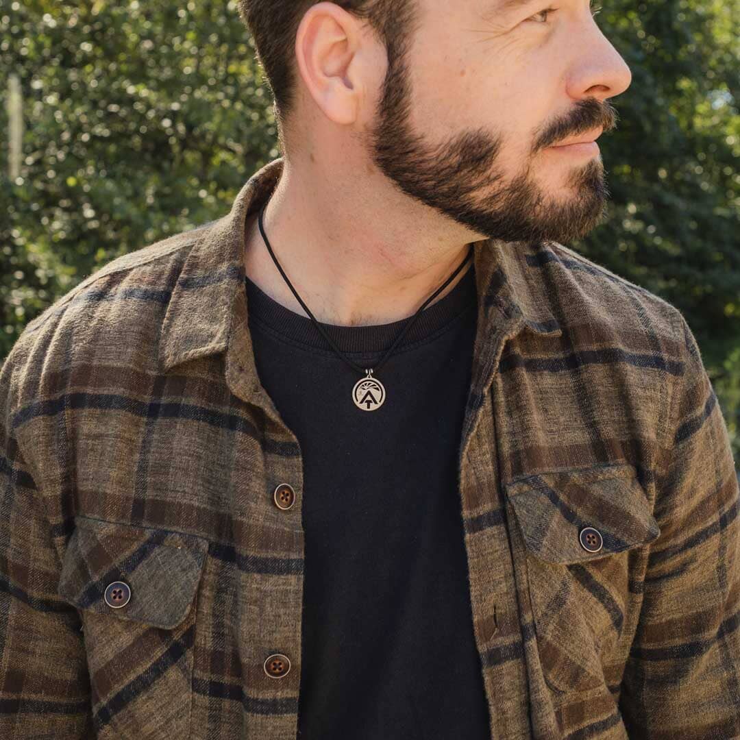 Man wearing stainless steel appalachian trail sunburst pendant on black paracord