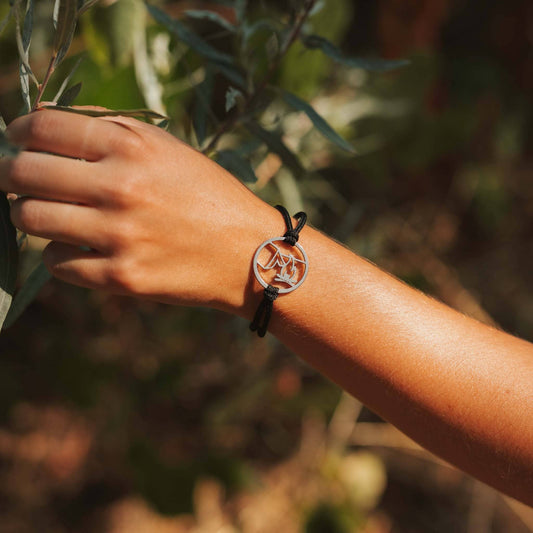 Girl wearing stainless steel campfire and tent pendant bracelet on black paracord