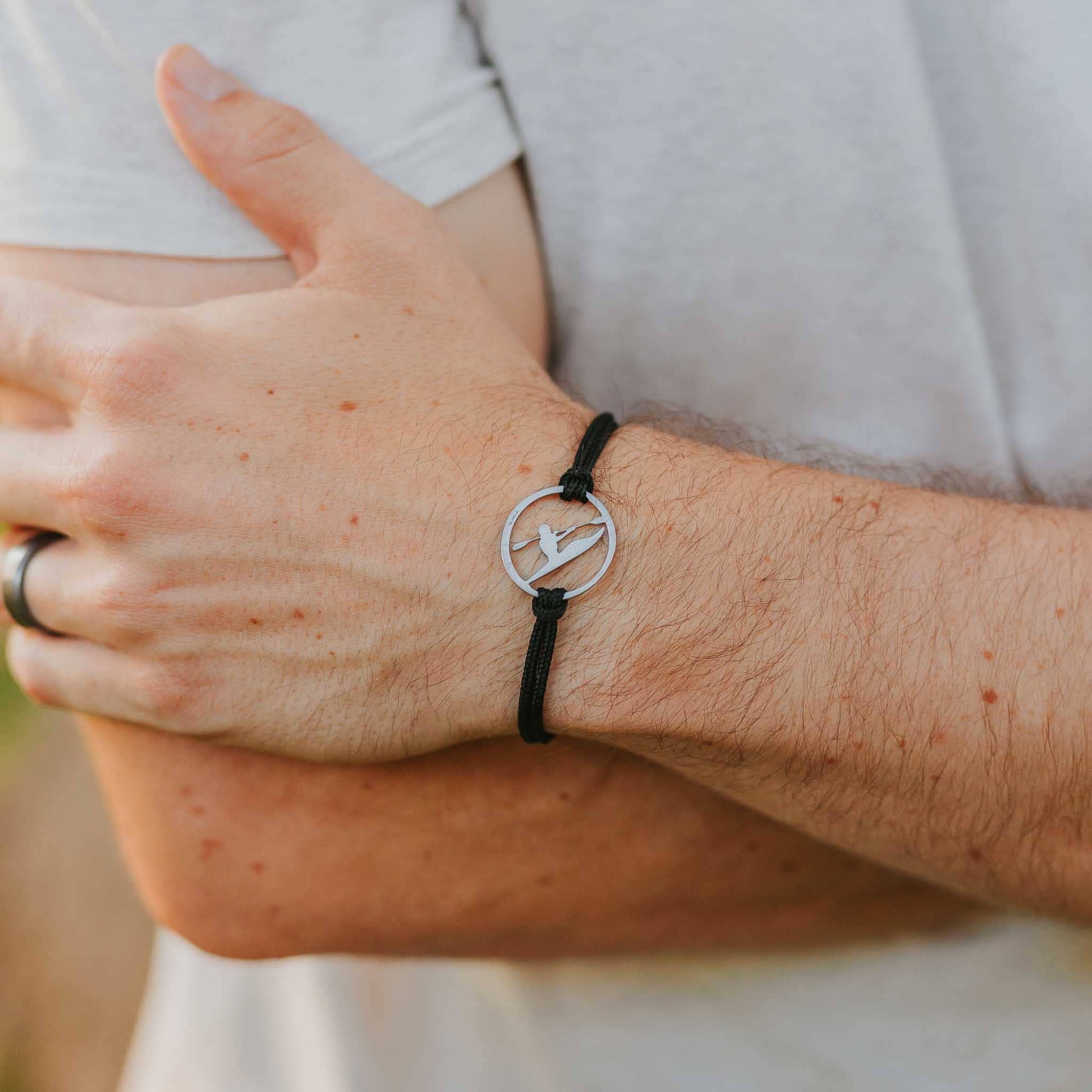 Man wearing stainless steel kayaker bracelet on black paracord