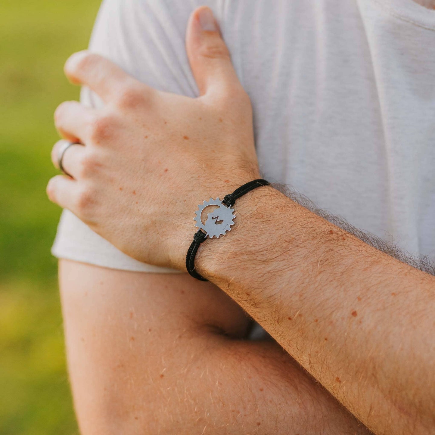 Man wearing stainless steel bicycle cog bracelet on black paracord