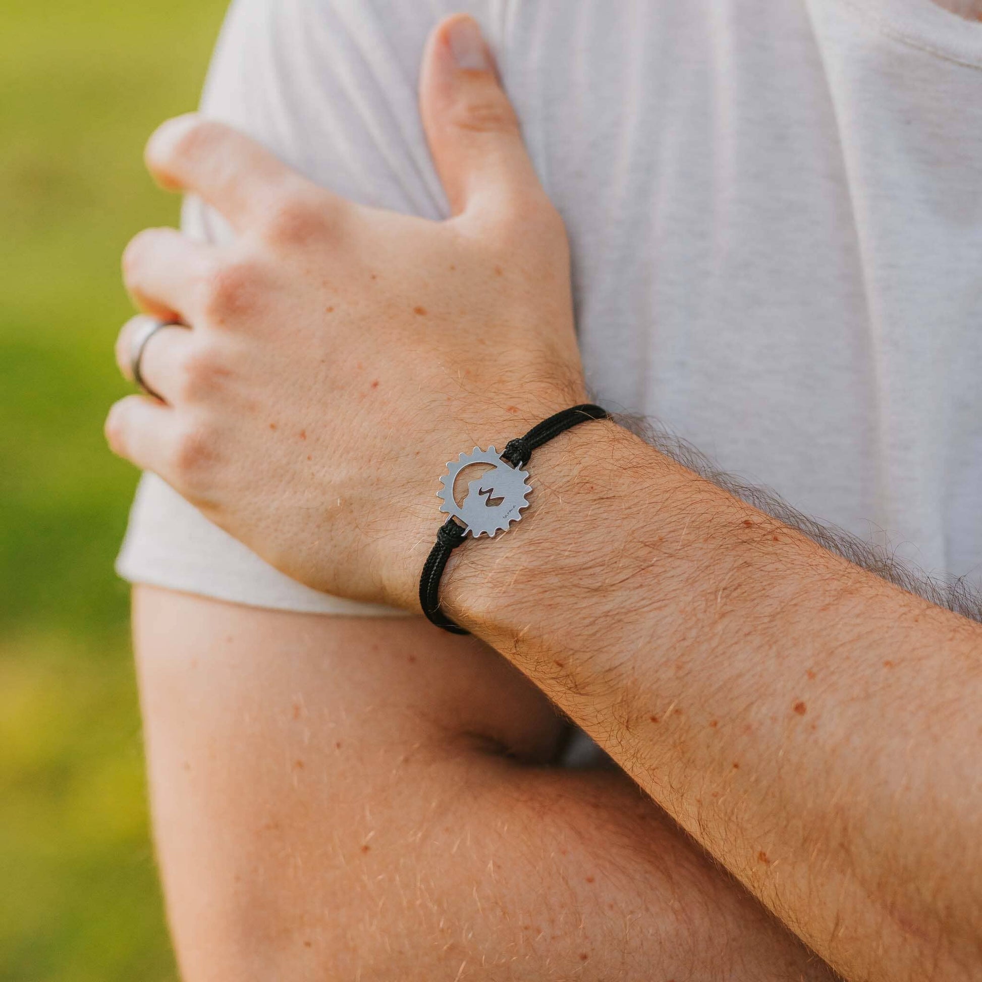 Man wearing stainless steel bicycle cog bracelet on black paracord
