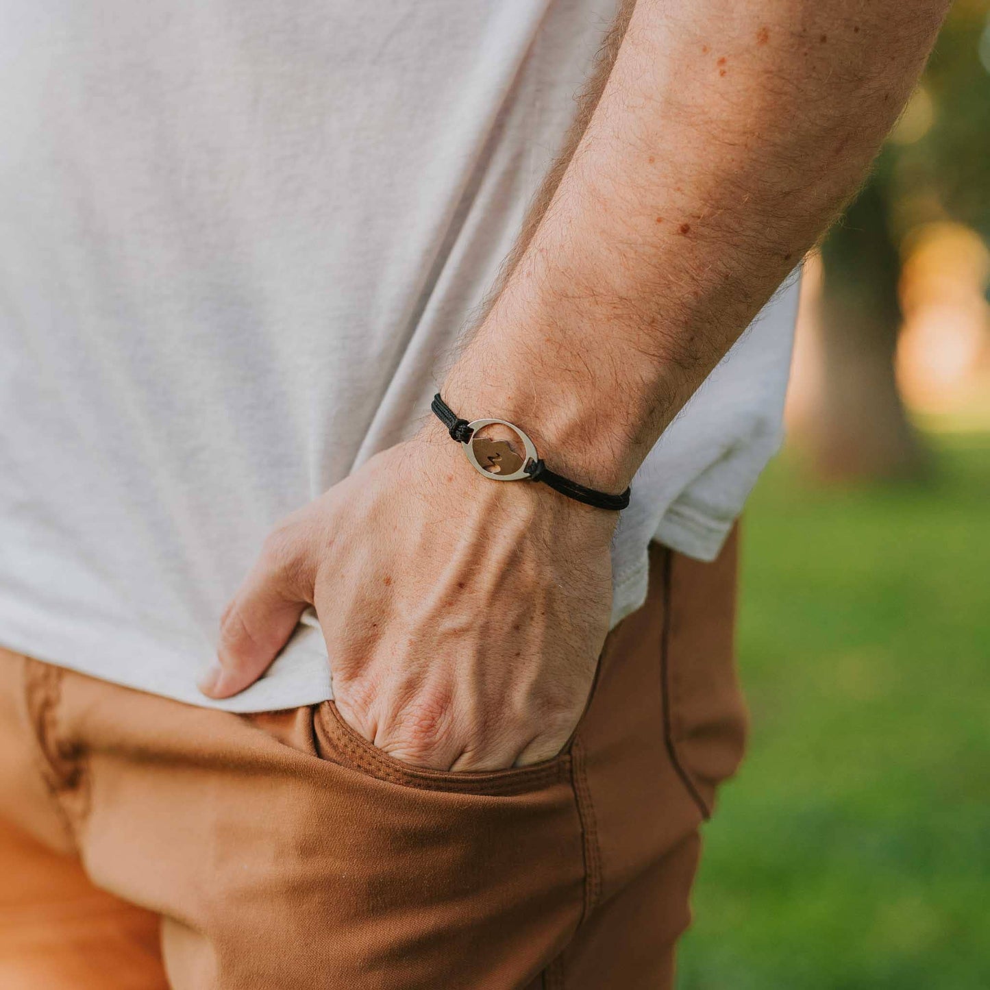 Man wearing stainless steel mountain and stream bracelet on black paracord