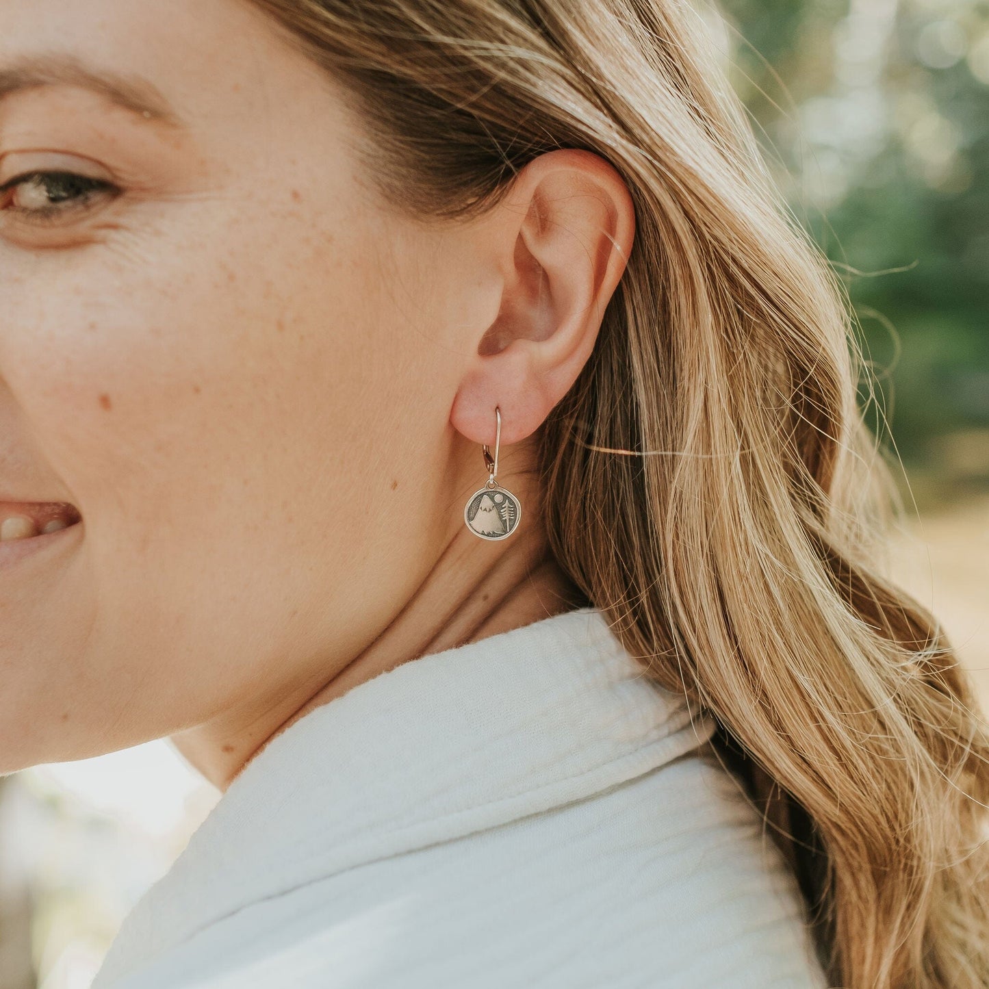 Girl wearing mountain and tree earrings in sterling silver