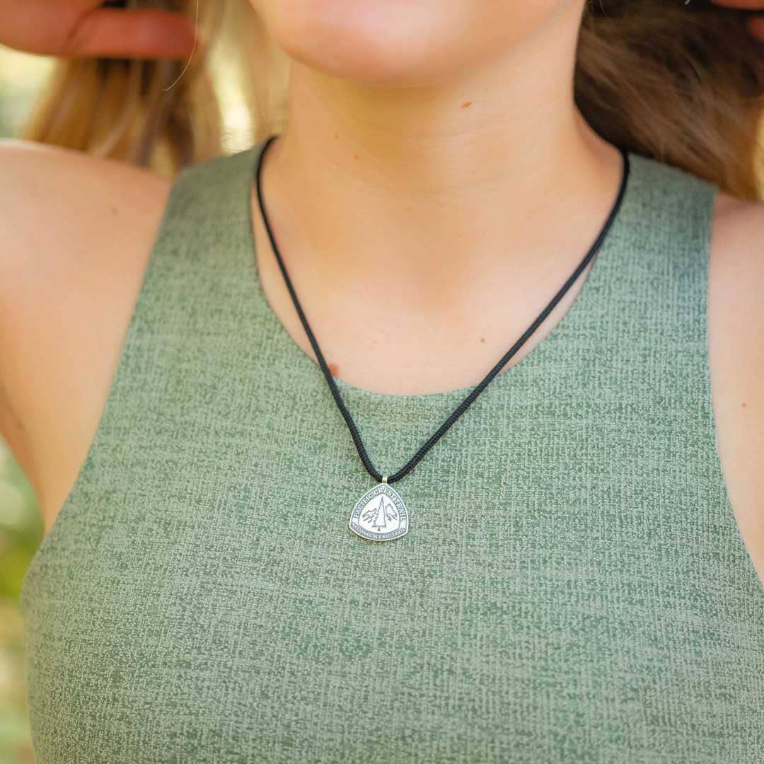 Women wearing white Bronze pacific crest trail marker pendant on black paracord