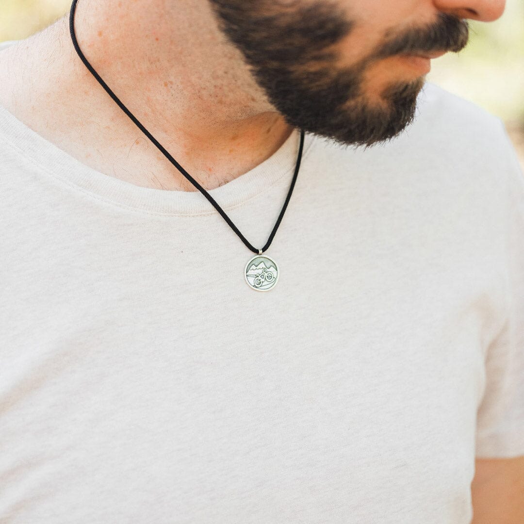 Man wearing sterling silver road bike pendant on black paracord