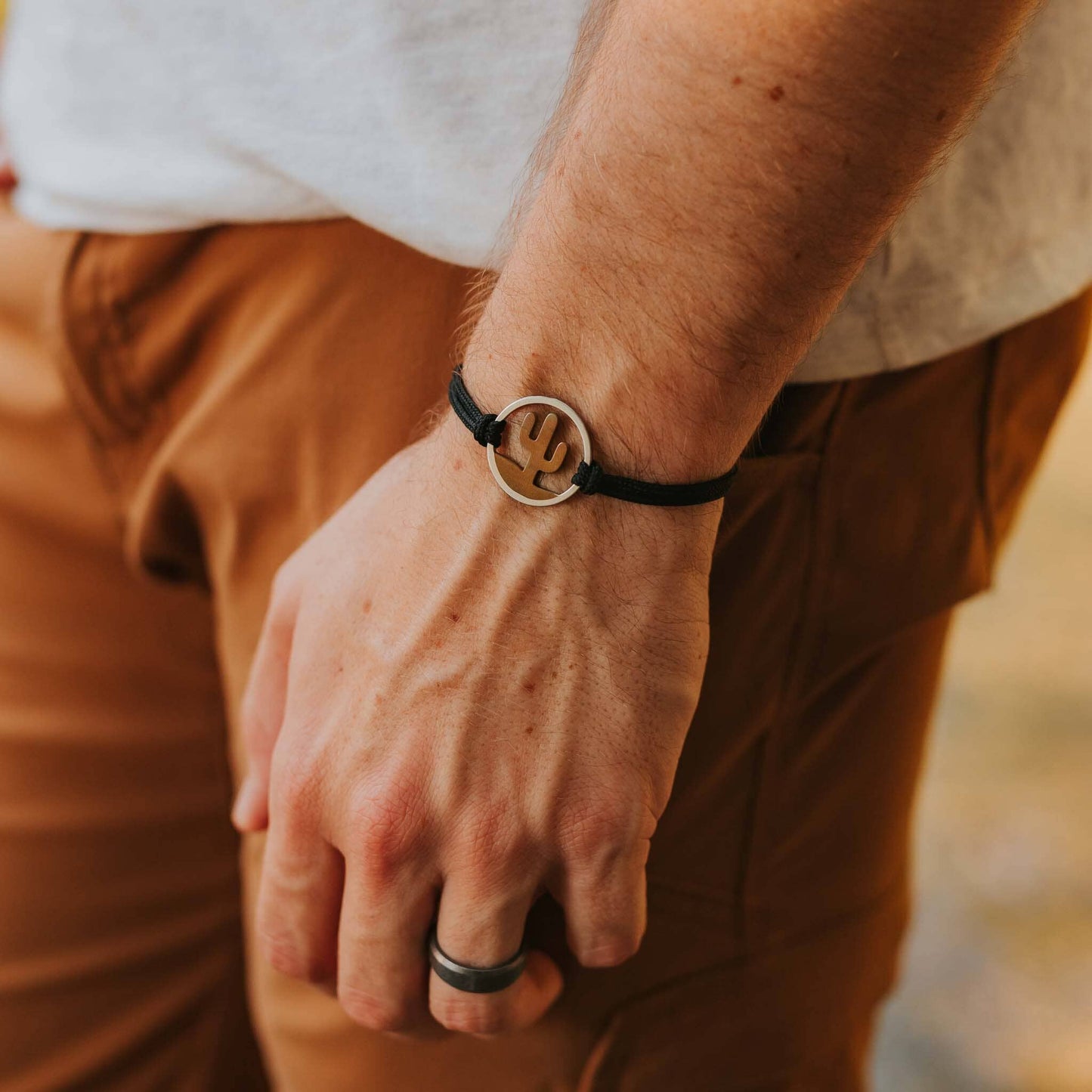 Man wearing stainless steel saguaro national park bracelet on black paracord