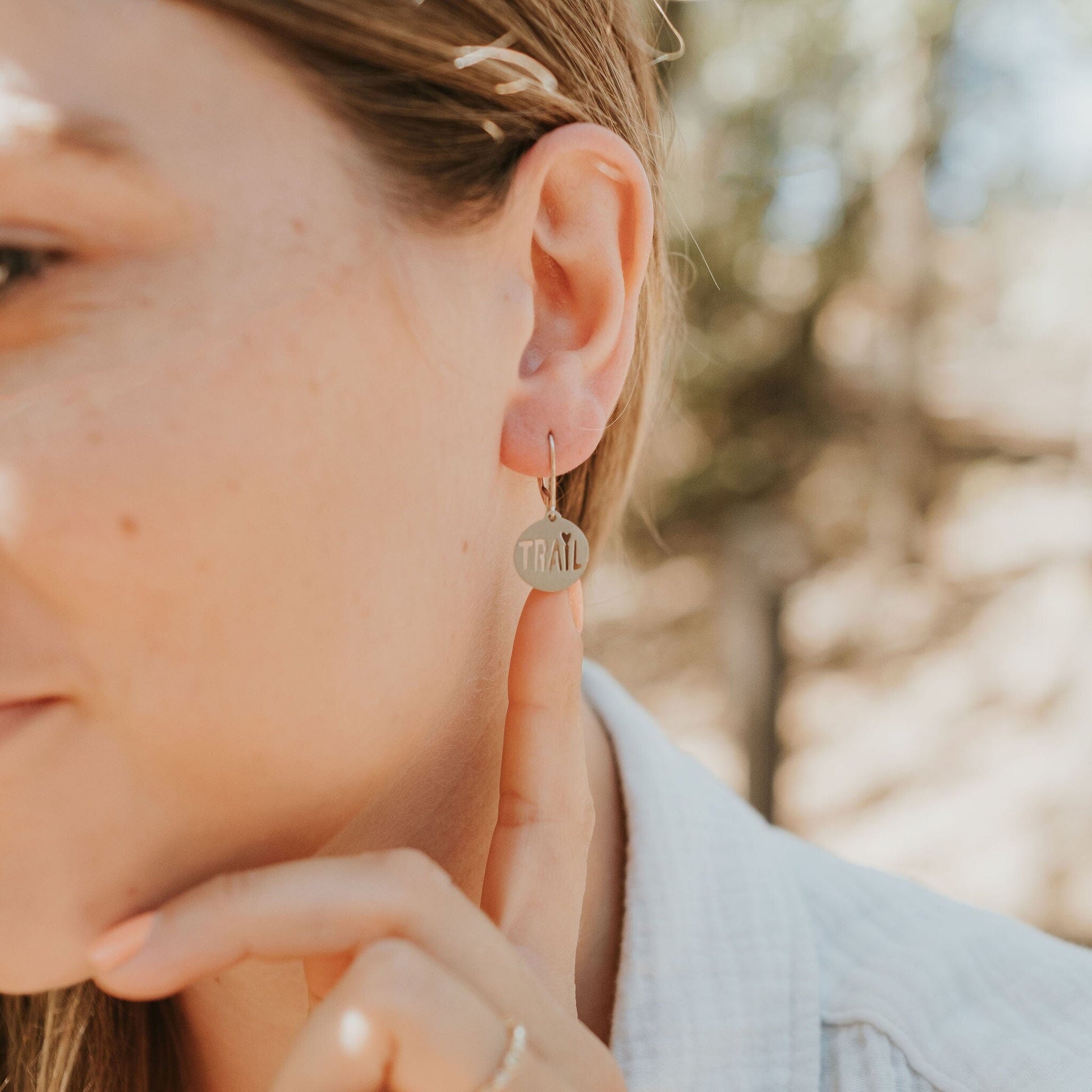 Girl wearing trail love earrings in stainless steel