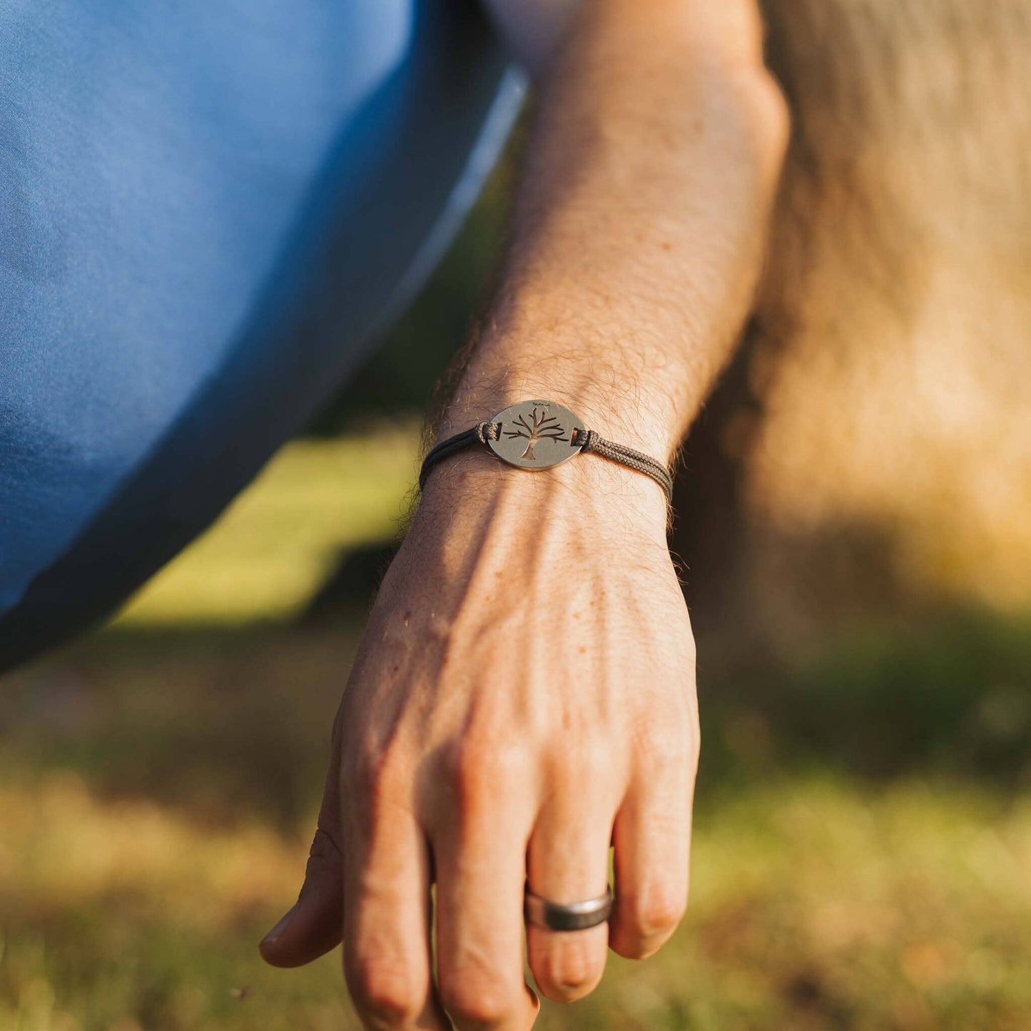 man wearing stainless steel tree of life bracelet on sage paracord while hammocking