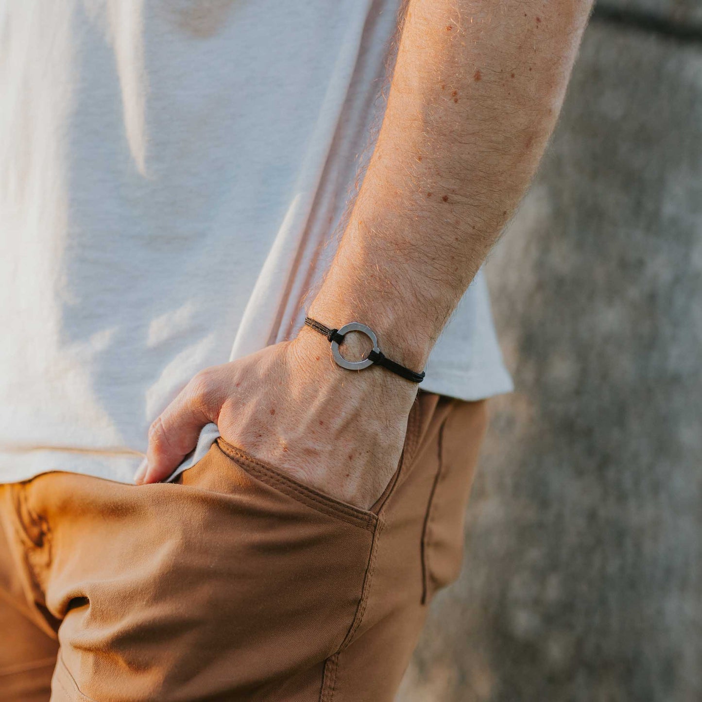 Man wearing stainless steel zen circle bracelet on slate paracord