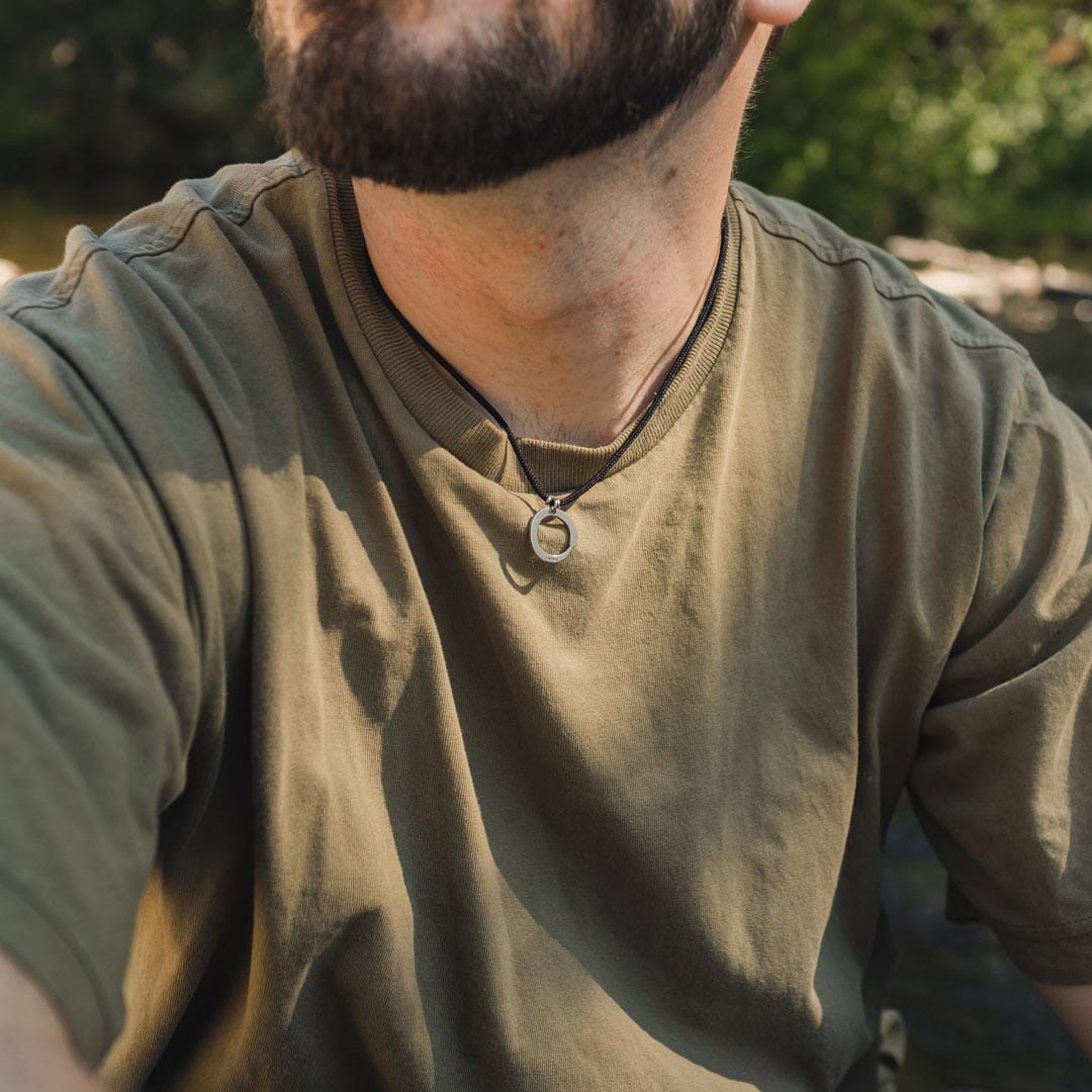 Man wearing stainless steel zen circle pendant on black paracord