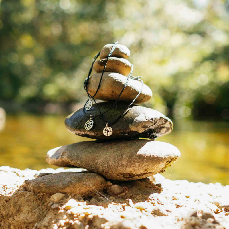 stacked stones with river in the background with tarma designs anklets laying on the stones