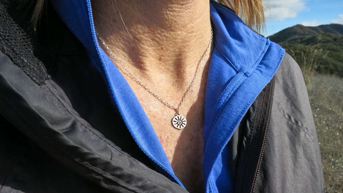 Sterling silver sun charm necklace worn on an 18-inch chain