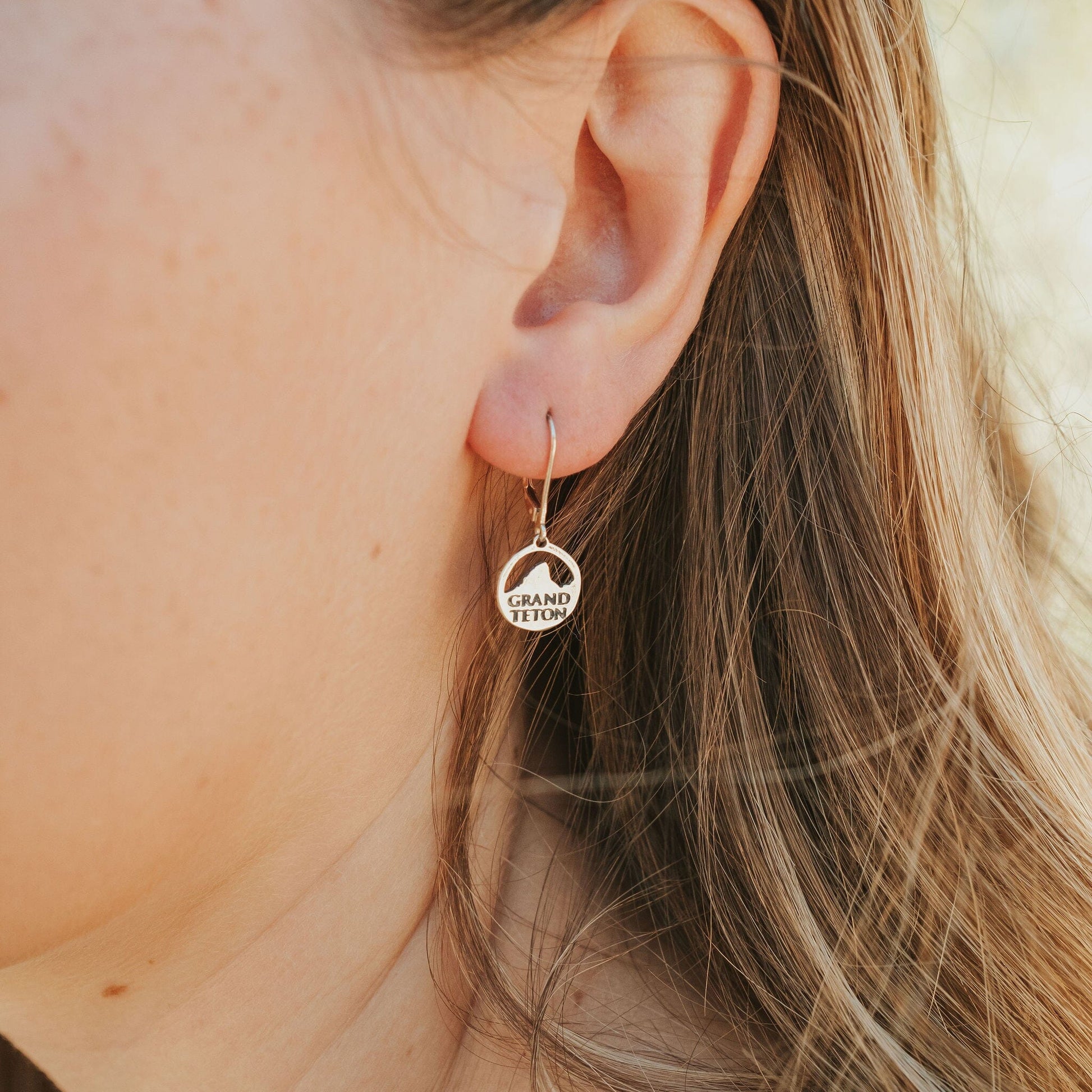 Girl wearing grand teton national park earrings in white bronze