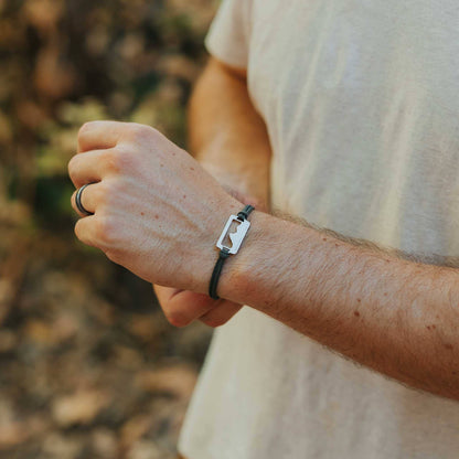 Man wearing stainless steel grand teton national park pendant bracelet on black paracord