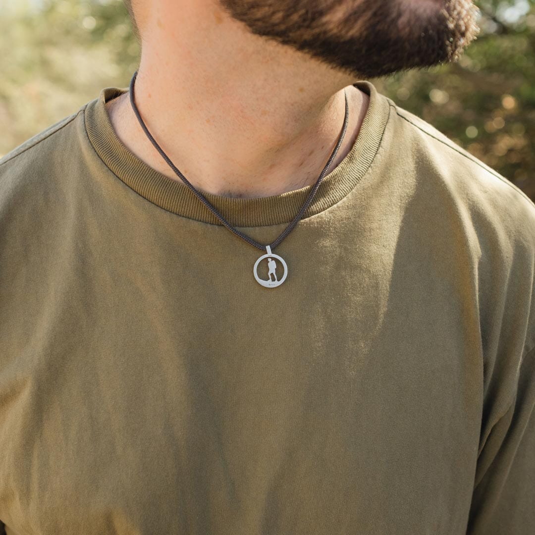 Man wearing stainless steel hiking guy pendant on slate paracord