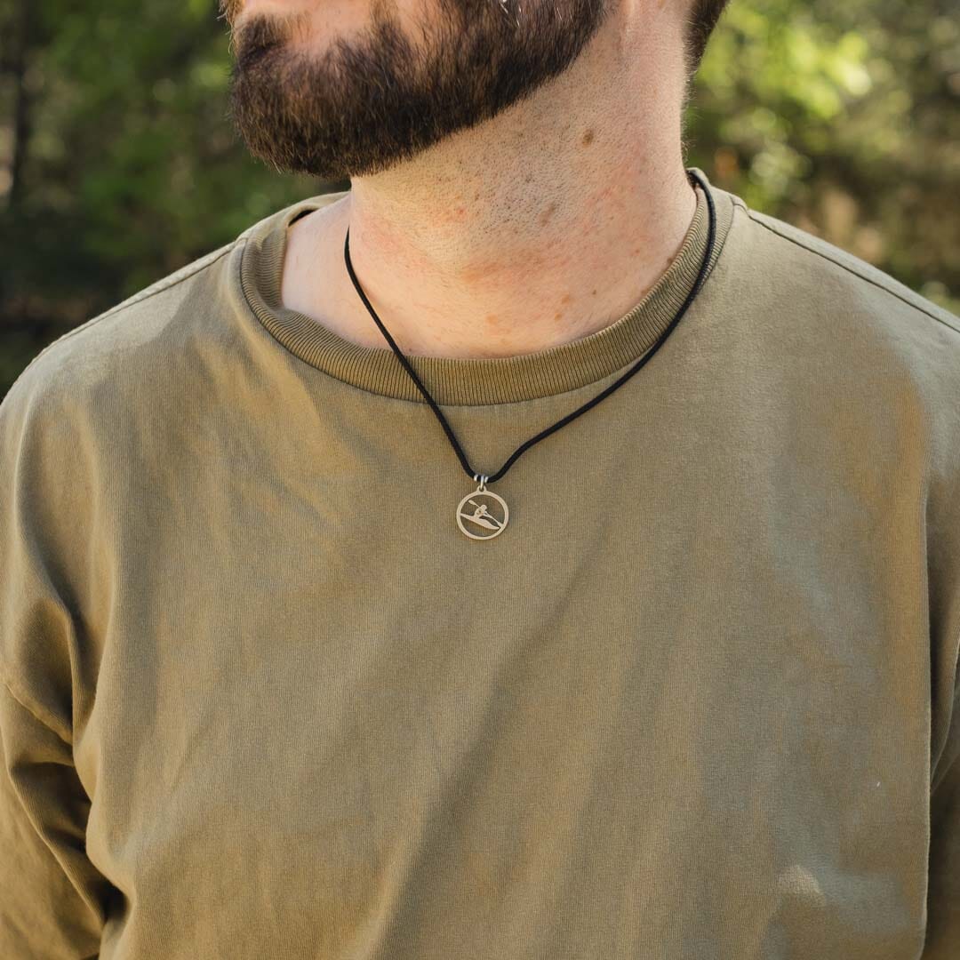 Man wearing stainless steel kayaker pendant on black paracord