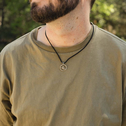 Man wearing stainless steel kayaker pendant on black paracord
