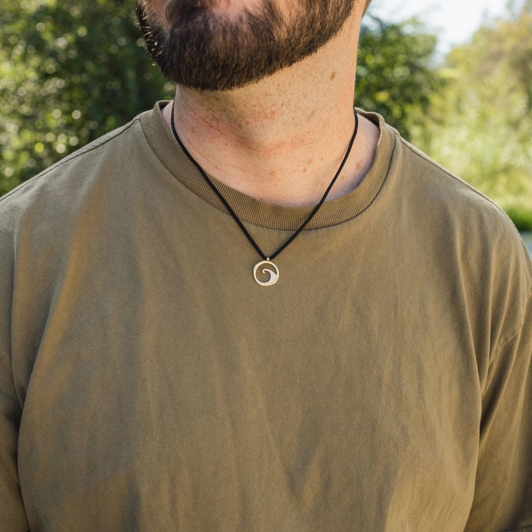 Man wearing sterling silver wave pendant on black paracord
